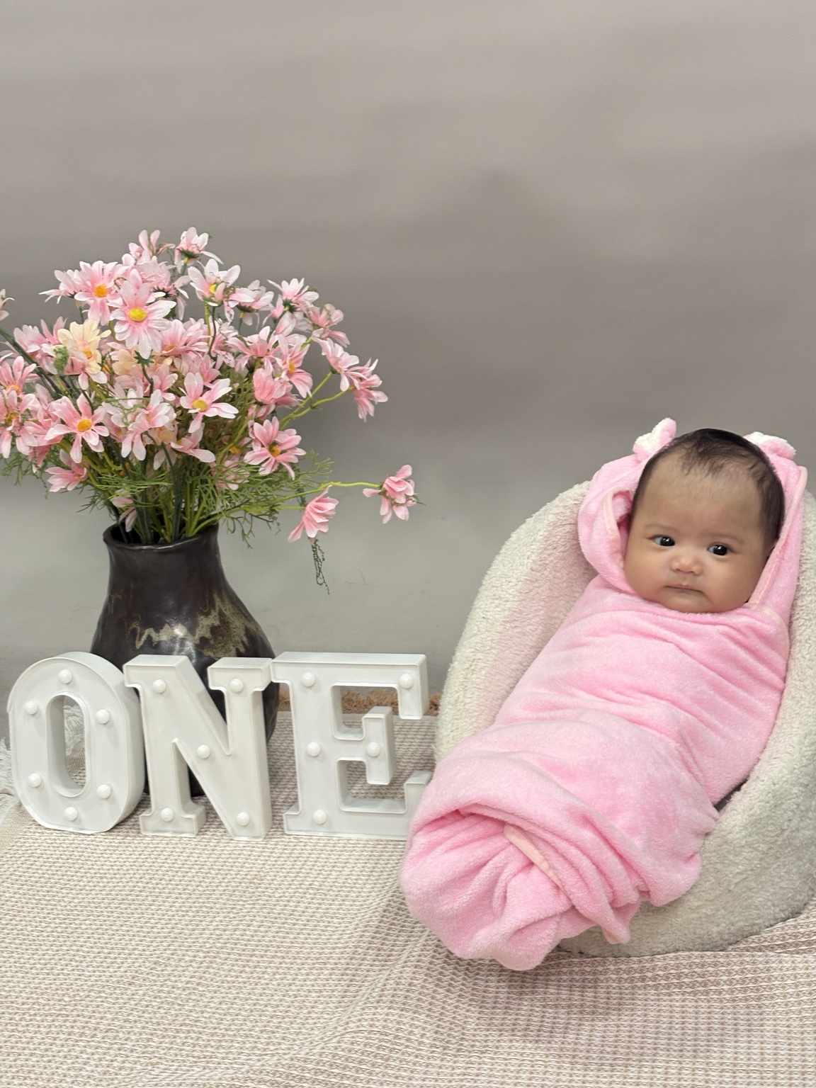Dorothea Maeve beside pink flowers and the word ONE